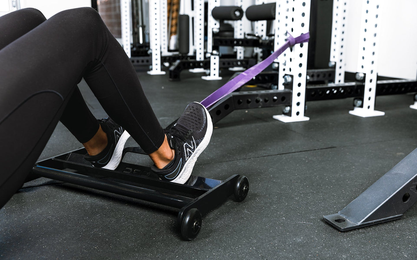 Athlete using glute ham roller with bands attached to a rack